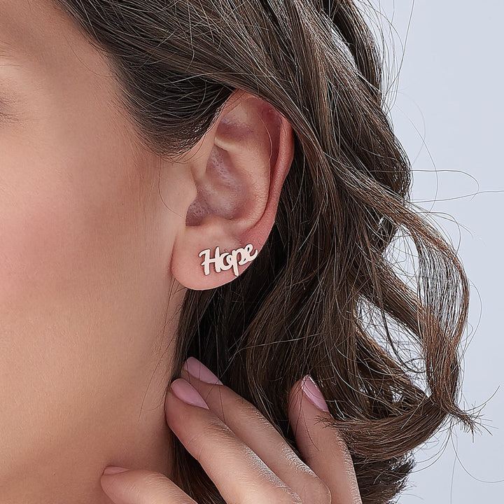 Custom arc name earrings worn by a model with short hair